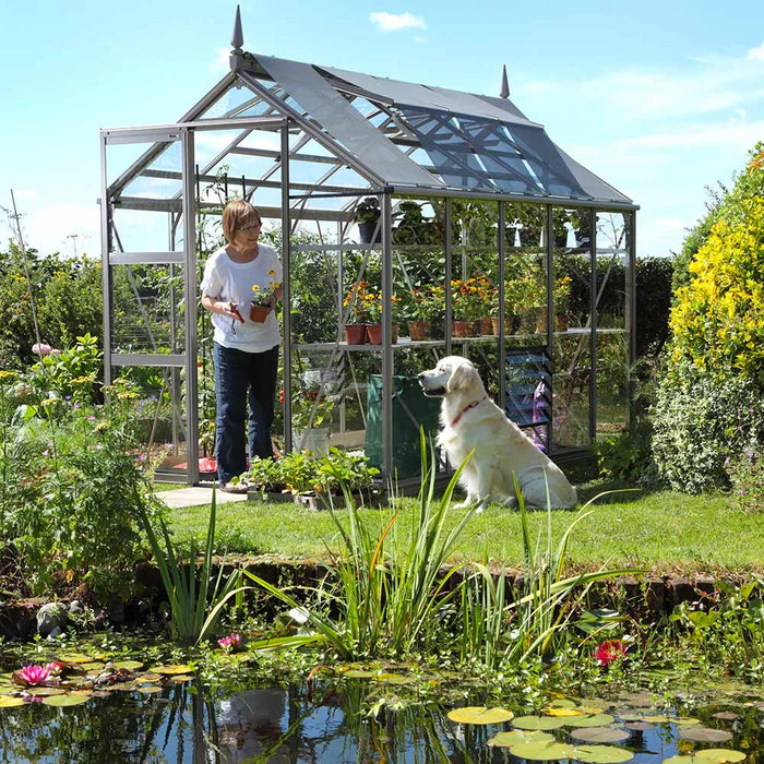A well landscaped garden with a pond and a Rhino premium greenhouse