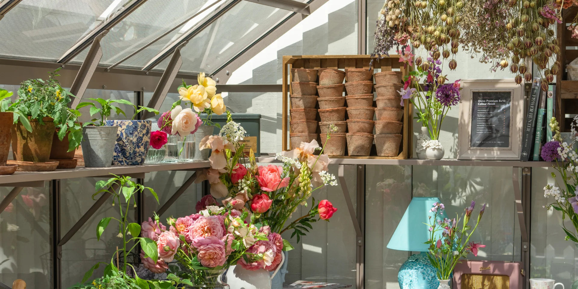 An assortment of decorative items on integral staging within a greenhouse